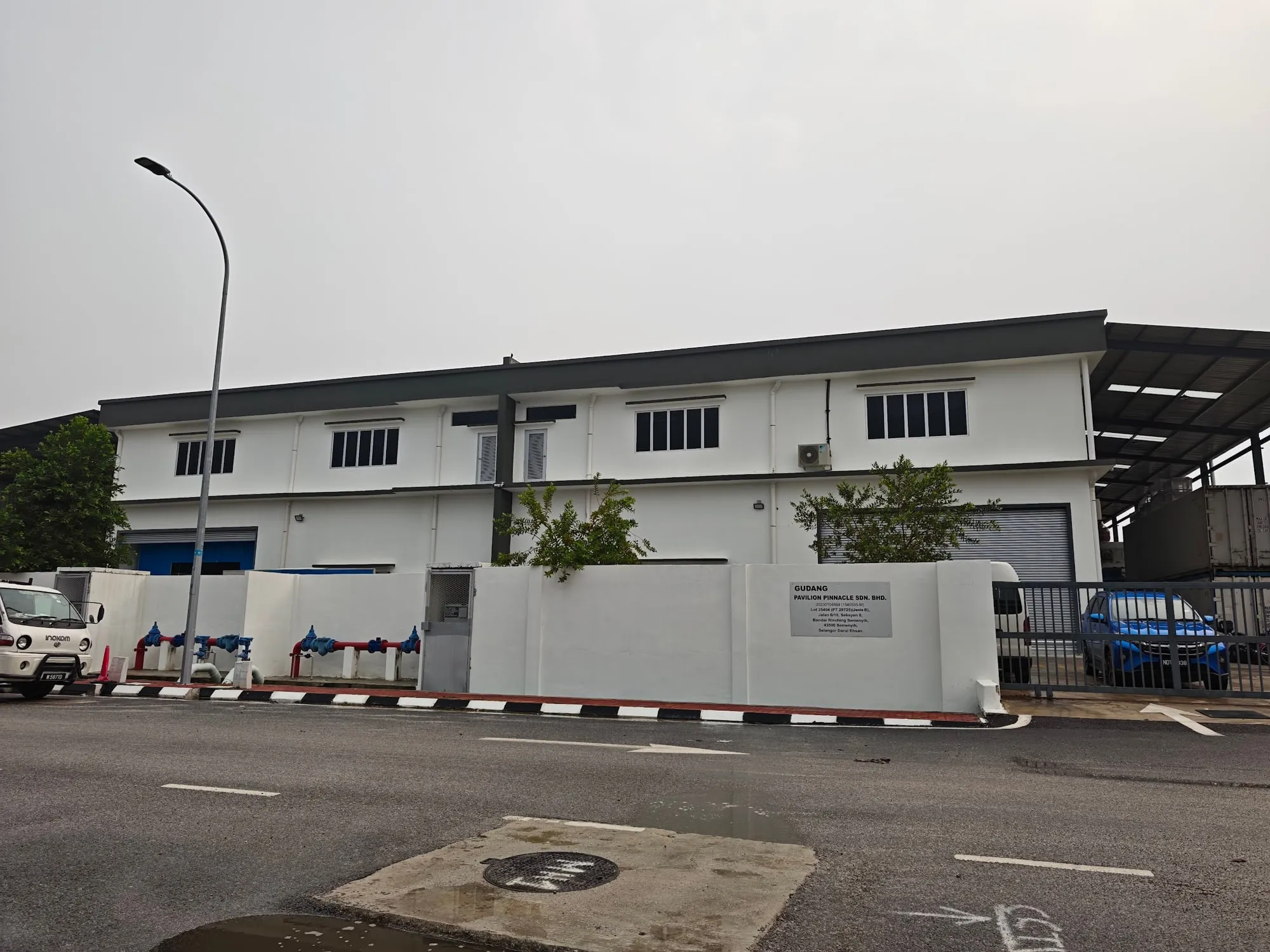 Two-storey warehouse seen from the street, with boundary wall and gated entrance